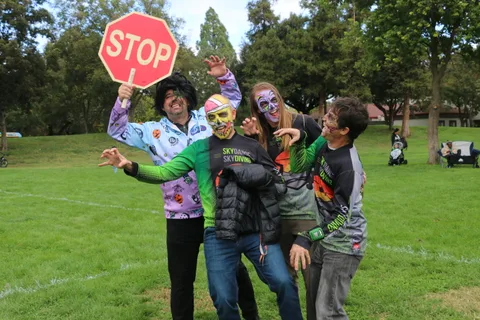 Three costumed festival-goers pose together with a stop sign.
