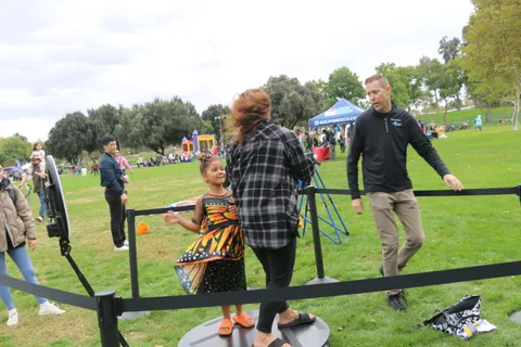 A girl in a butterfly costume stands at an archery target range.