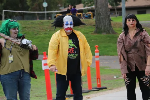 A performer and clown share an animated moment on the grass.