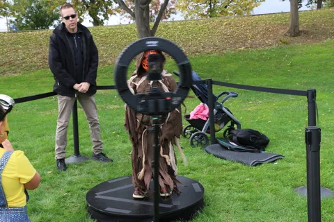 A child in a scarecrow costume stands on a 360-degree photo booth platform.