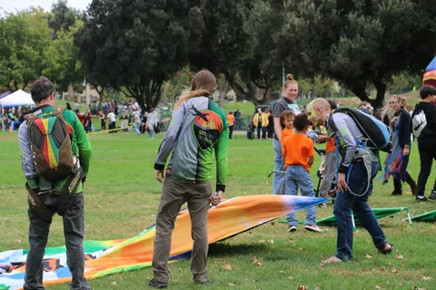 Men in colorful costumes unroll a large painted tapestry banner on the grass.
