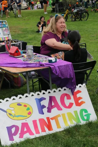 A hand-painted sign advertises face painting at the festival.