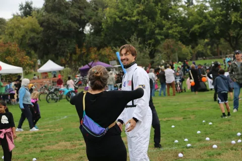 A person in an astronaut costume gestures while talking with another festival-goer.