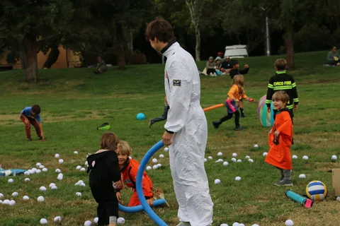 A person in a white astronaut costume stands bent forward in a grassy field.