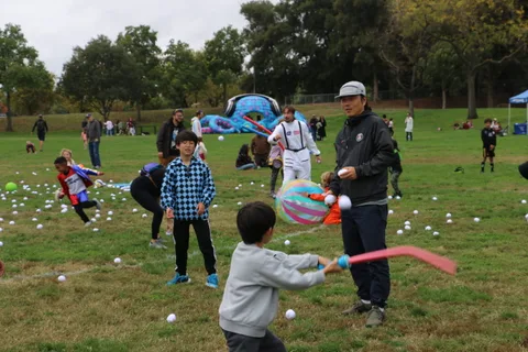 Children play a lawn game with a colorful ball among scattered white balls.