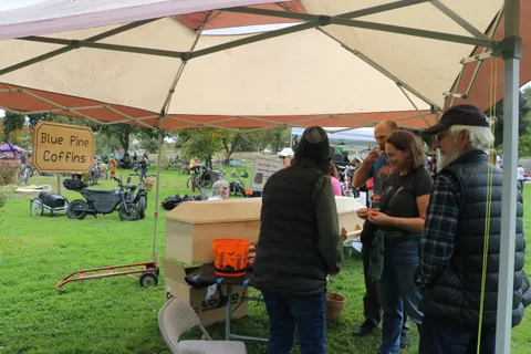 A view under a tent canopy with festival-goers gathered in the background.