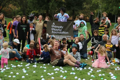 Children in bee costumes join a large costumed group photo in the park.