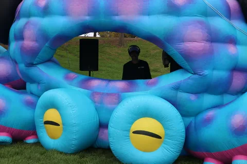 Close-up of a large blue inflatable creature sculpture with big yellow eyes.