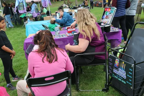 A busy face painting booth with several children waiting their turn.