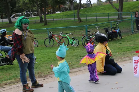 A zombie performer walks behind two costumed children on the path.
