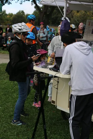 Cyclists in helmets gather near a tent booth amid a crowd at the festival.