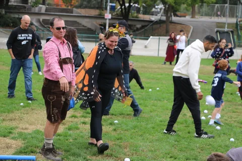 A man in butterfly wings walks with a woman in an orange and black dress.