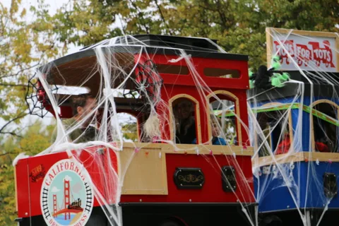 A decorated red trolley car with a circular emblem sits wrapped in spiderwebs.