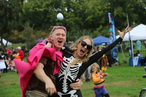 A man in a skeleton costume embraces a woman under his pink cape.