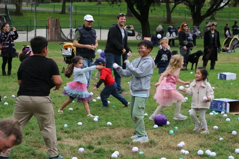Kids run with balls flying near the playground area.