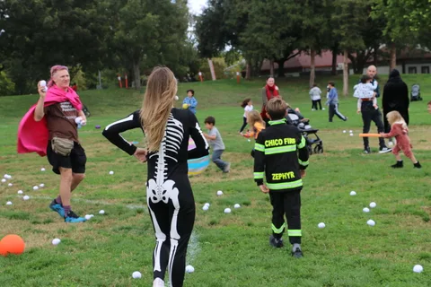 Two people in costume stand with their backs to the camera in a park.