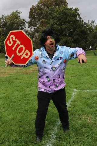 A man holds a stop sign and shouts playfully with arms outstretched.