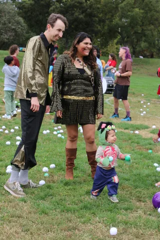 A couple in glamorous gold and sequin costumes smile together at the festival.