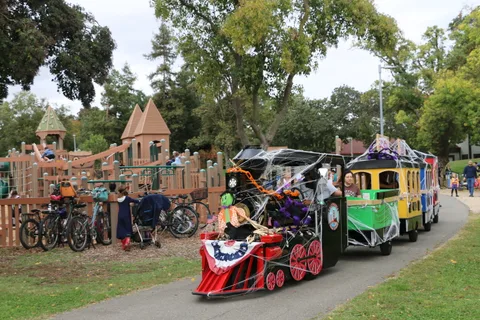 Decorated parade trains sit parked near a castle-themed playground.