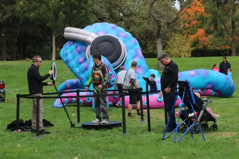 A man adjusts target equipment near a giant inflatable caterpillar sculpture.
