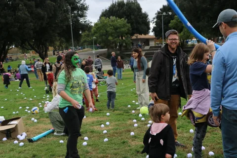 A woman in zombie makeup talks with a man and boy holding a pool noodle.
