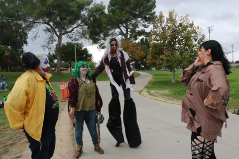 Costumed performers walk away down the park path.