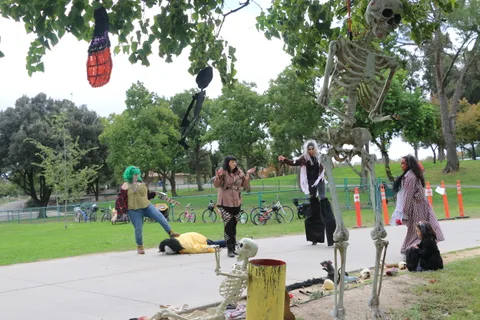 Skull decorations hang from tree branches over the park path.