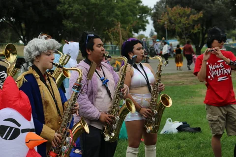 Three costumed saxophone players pose together in the park.