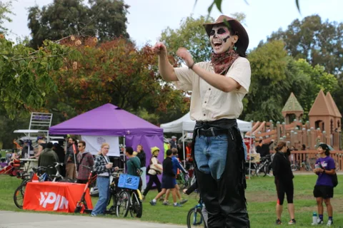 Two people in face paint costumes stand together near event tents.