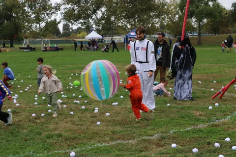 Kids run through a field scattered with white balls during a lawn game.