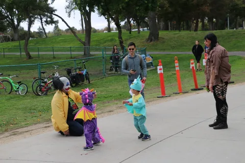 A child in a dragon costume and a child in a dinosaur costume play together.