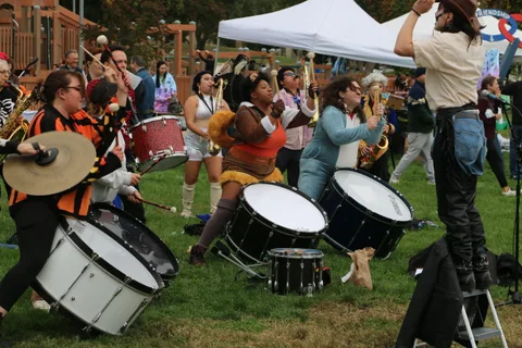 A drummer on a raised stool strikes his cymbal high above the drum line.
