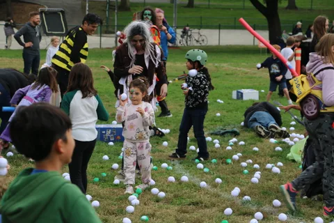 Costumed kids stand amid scattered balls on the grass.