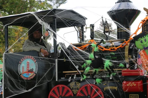 A driver sits at the front of a decorated Halloween parade train.
