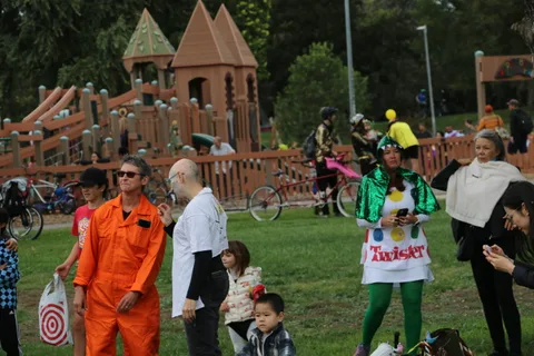 A spread out crowd in orange jumpsuits mingles near the play structure.
