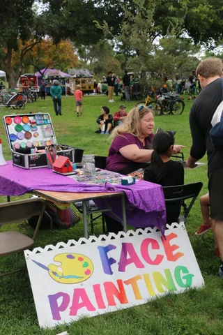 A face painting sign leans against the booth setup.