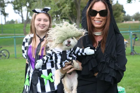 A smiling girl poses in costume as a woman moves beside her.