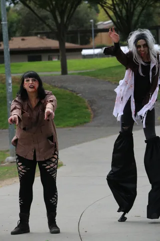Cropped view of a stilt walker's legs on the path.