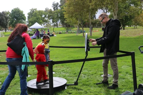 A mother watches her costumed child on the spinning platform ride.