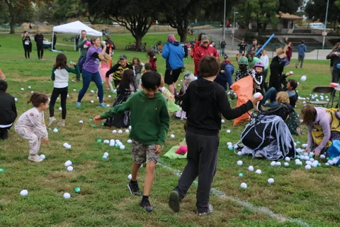 People run across the grass among scattered white balls.