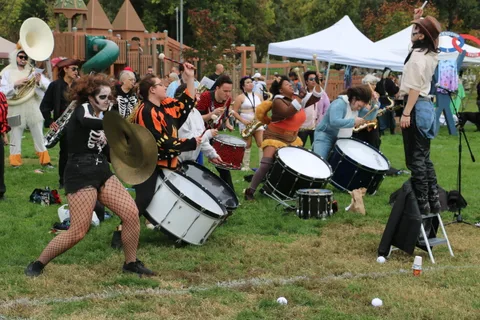 A drummer in skeleton makeup strikes her cymbals mid-performance.
