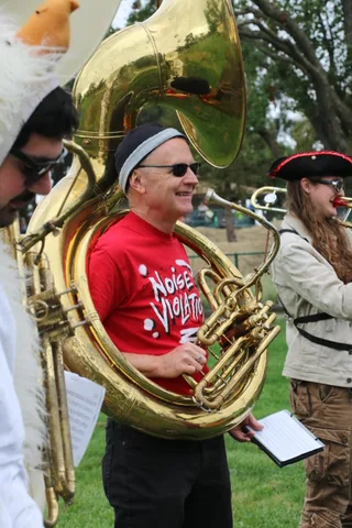 A cowboy-hatted musician plays a sousaphone in profile.