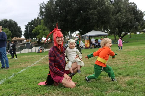 A boy jumps beside his family dressed in lobster and lamb costumes.