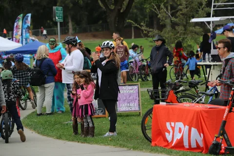 Families gather near tents and a Spin banner in a cluttered scene.
