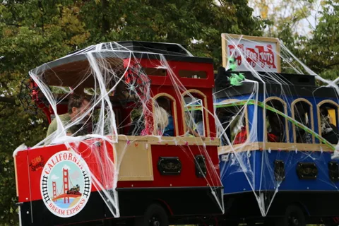 A red trolley car with a partly visible banner sits decorated with spiderwebs.