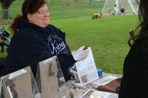 A smiling volunteer stands behind an informational booth table.