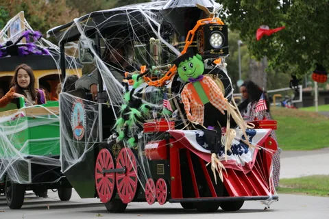 A cobweb-covered locomotive with a green zombie figure leads the Halloween parade train.