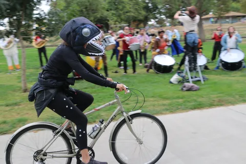 A rider in a skull-face helmet pedals a bike alone.