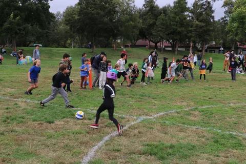 Costumed kids run across the field as the ball-toss game begins.