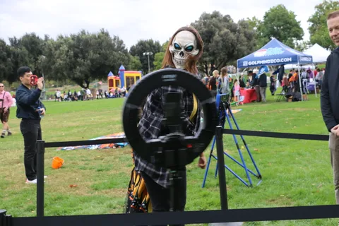 A man stands near an archery target while a girl in a butterfly costume waits nearby.